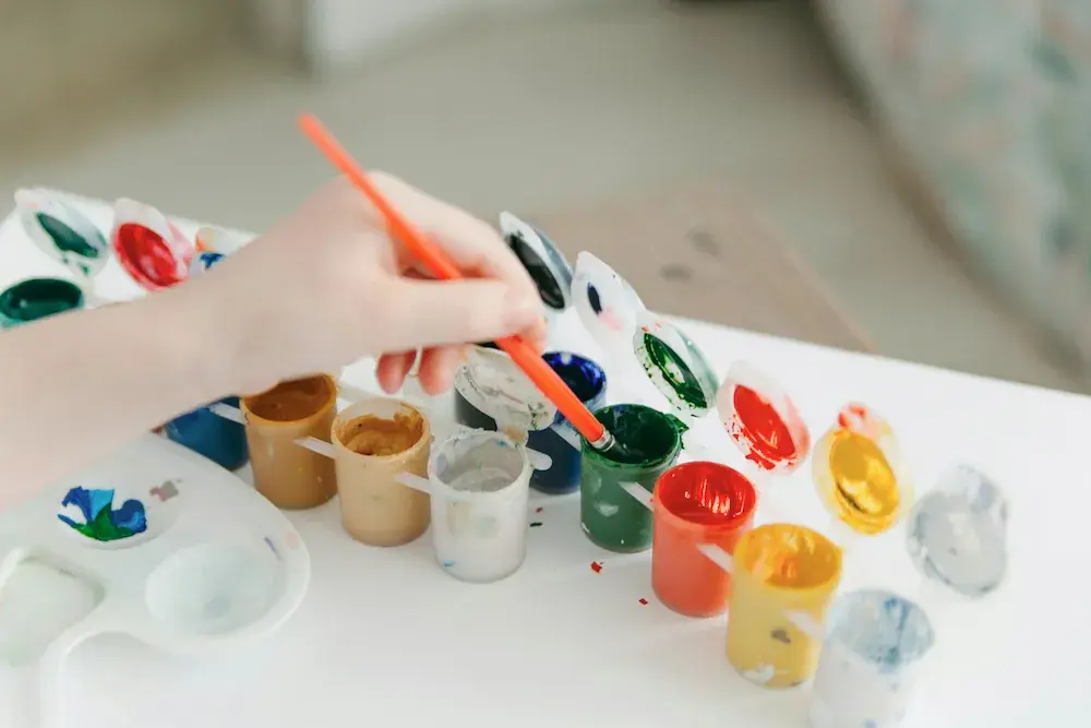 Children's hands with paintbrushes creating art